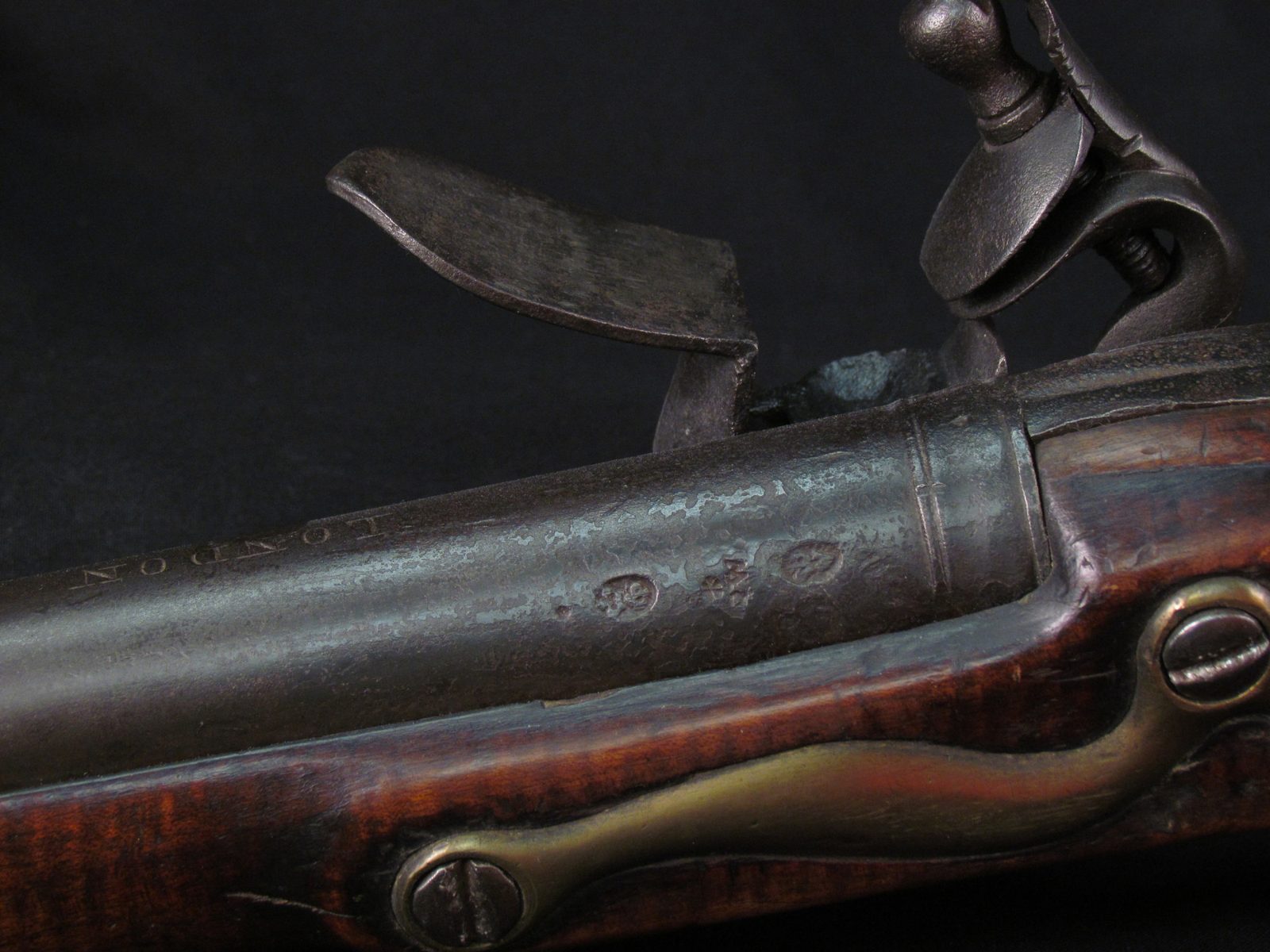 Lock and breech of a 1761 Brown Bess musket: the frizzen, the cock holding its flint, and the proof marks on the barrel